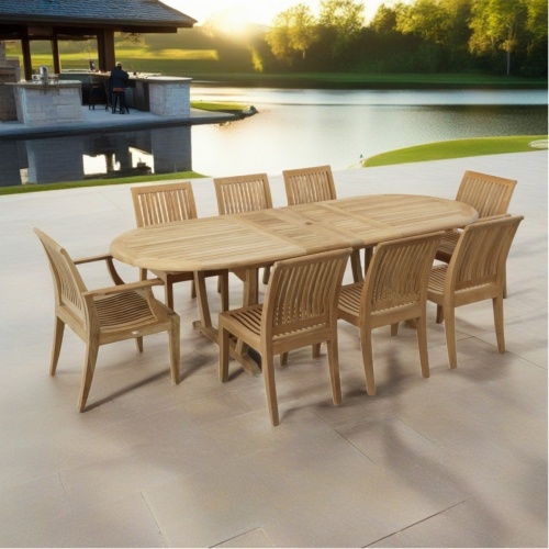 70926 Laguna Montserrat 9 piece Dining Set angled view on paver patio overlooking a lake with trees and a gazebo in the background