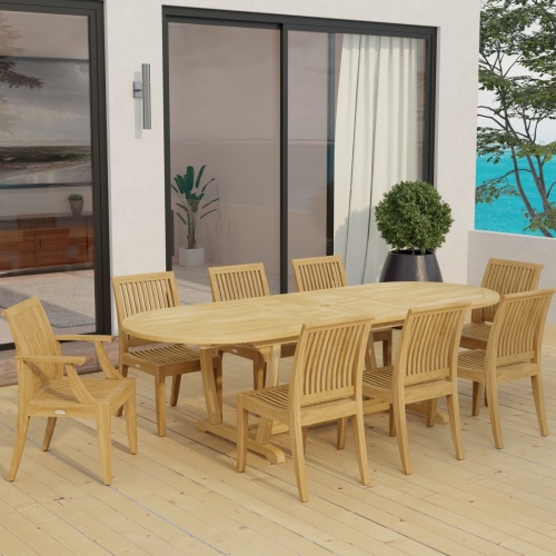 70926 Laguna Montserrat 9 piece Dining Set of Montserrat Oval Teak Table and 2 Laguna Dining Armchairs and 6 Laguna Side Chairs in side angled view on patio with house in background