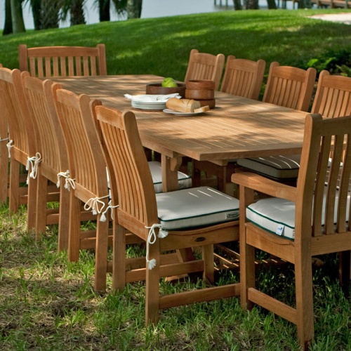 11315RF Veranda teak dining side chair with seat cushions with Veranda dining set on grass lawn and palm trees in back