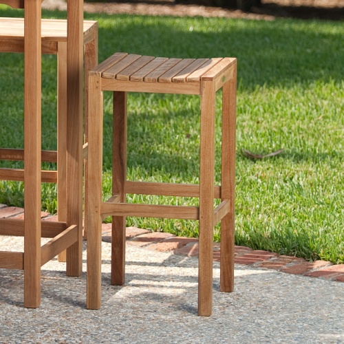 12110 somerset backless barstool side view on white brick patio with grass field in background