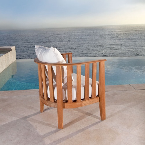 12170dp Kafelonia teak club chair with cushions back angle outside on concrete patio overlooking pool and ocean in background