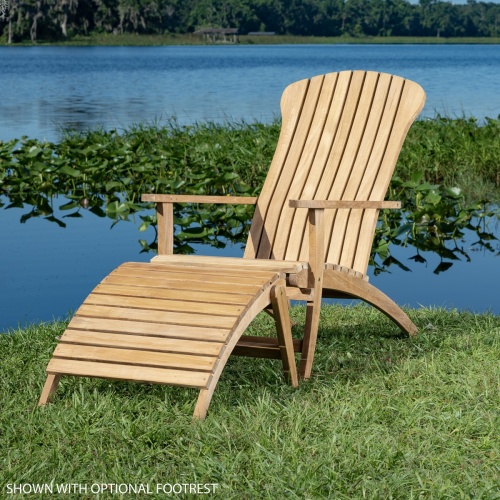 12221 Adirondack chair with optional footrest on green grass side view with lake with water lilies and plants in background