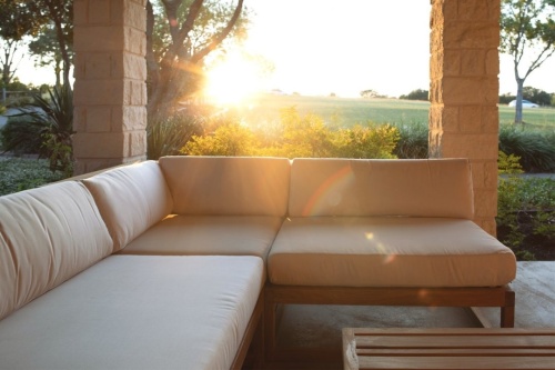 13800dp maya sectional collection on patio surrounded by landscape plants with view of grassy field with sunset in background 