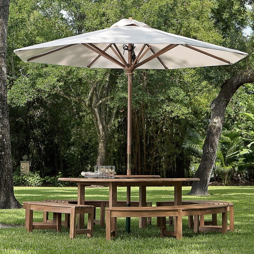 17542 teak round ten foot market table umbrella with white canvas canopy extended with round curved bench patio set on a green lawn with trees in background