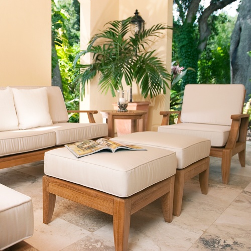 18652 Laguna sofa set on outdoor tile patio with open magazine on cushioned ottoman candle on side table potted palm tree with lush background 