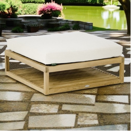18800DP Maya Ottoman with cushion angle view on pavers with lake and landscaping plants in the background