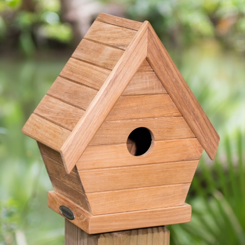 19003 teak bird house on fence post on grass with trees in background
