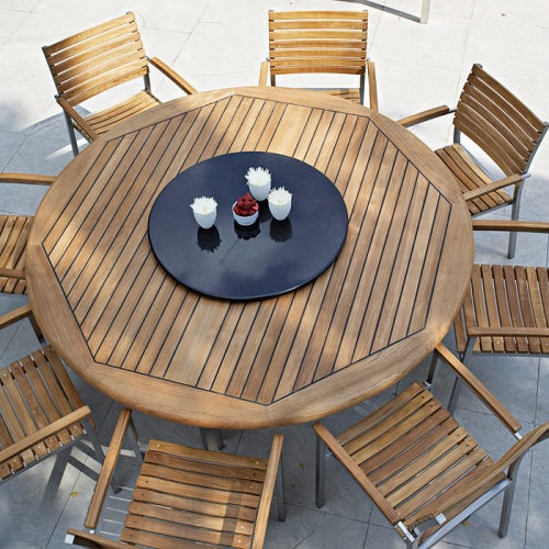 25015 Vogue teak and stainless steel 6 foot Round Table with 9 piece Vogue Dining Set with black lazy susan in center on a concrete patio overhead view