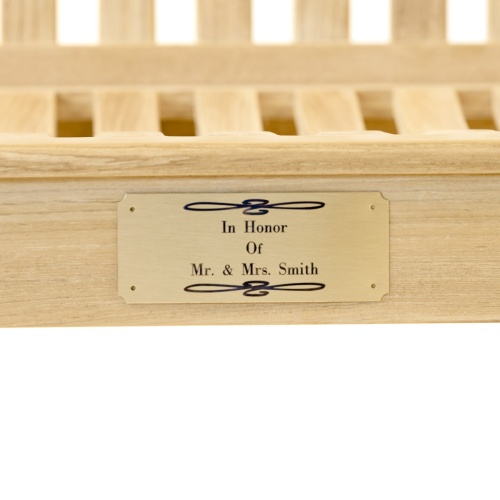42000 Personalized brass Plaque shown on underside seating area of a teak bench on a white background