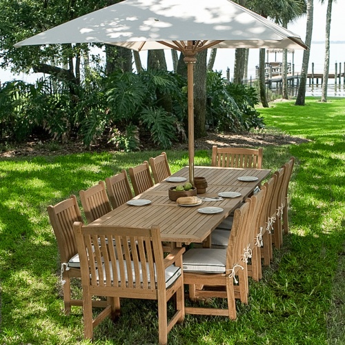 70017 Grand Veranda 13 piece dining set with optional seat cushions and optional market umbrella bowl of apples a plate of bread wood bowls plates on grass with dock and lake background