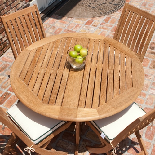 70036 Barbuda teak 5 piece round Dining Set with optional seat cushions and table showing glass bowl of green apples aerial view on brick patio