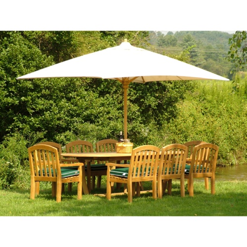 70068 montserrat curve nine piece oval dining set basket wine with glasses open market umbrella side view on green grass lawn with creek and vegetation background