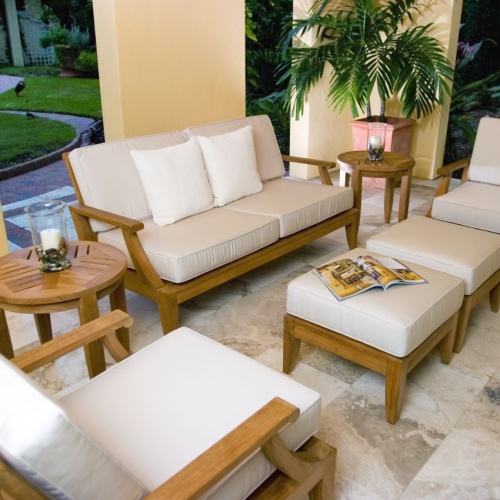 70105 laguna seven piece sofa set on patio aerial view with two pillar candles in glass holders on side tables open magazine on ottoman potted palm landscaped grass area in background