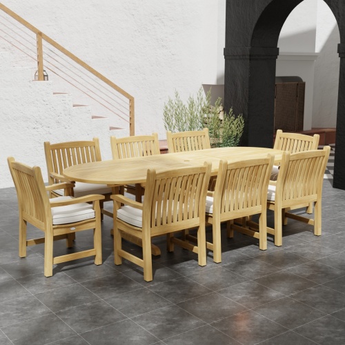 70178 Montserrat Veranda Teak 9 pc Dining Set side angled view on outdoor patio with potted plant and staircase of house and black archway in the background