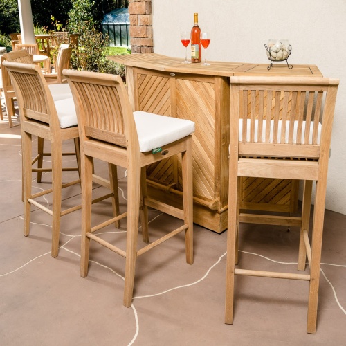 70419 Somerset 5 piece Laguna High Bar Set on paver patio with bottle of wine and 2 glasses glass bowl with stones on bar against a wall with landscaped background