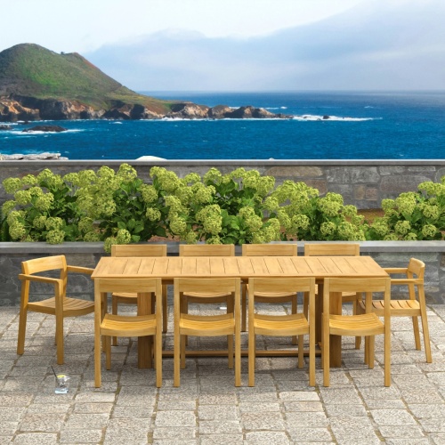 70457 Horizon 11 pc Teak Dining Set of Horizon Rectangular Teak DIning Table and 2 Teak Dining Armchairs and 8 Teak Side Chairs in side view on patio with ocean in background