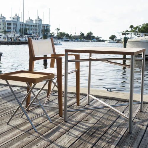 70460 Odyssey 3 Piece Teak and stainless dinette set on wood dock in a marina with boats and condominium and trees in background