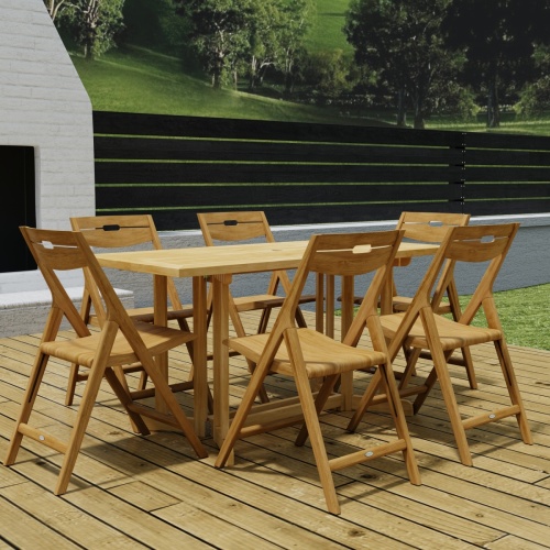 70472 Surf Nevis Teak 7 pc Dining Set of Nevis Dining Table and 6 Surf Folding Chairs in angled end view on wood deck with fireplace and fence with trees and hillside in background