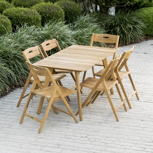 70518 Surf 7 piece teak folding Dining Set on paver patio with landscape plants and shrubs in background