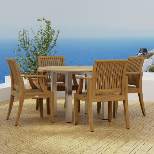 70620 Vogue Laguna Dining Set of Vogue Stainless Steel and Teak 4 ft Round Table and 4 Laguna Teak Dining Chairs on Teak Parquet terrace with potted plant and ocean in background