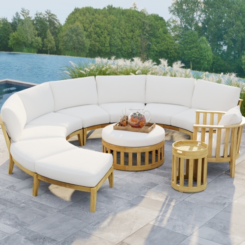 70864 Kafelonia 7 pc Lounge Sofa Set in angled front view with tray of Sangria and 2 glasses on Ottoman on tiled patio in front of Sea Oats and next to pool with a lake and trees in background