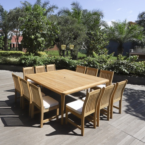 70879 Veranda 13 piece teak Square Dining Set with optional seat cushions angled view on deck with trees shrubs and buildings in background