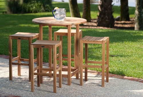 12110RF Somerset Backless Barstool Refurbished with round teak table and 4 backless barstools in side angled view on patio with grass and trees in background