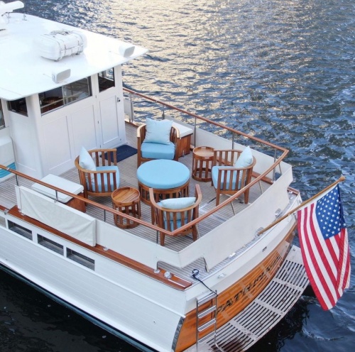  12170dp Kafelonia teak lounge set in marine gloss finish on boat deck in ocean with American flag on the stern 