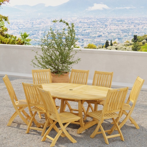 70060 Barbuda Martinique 9 pc Dining Set in angled side view on outdoor terrace next to potted tree with hillside view in background 
