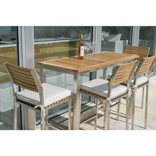 70076 Vogue 5 piece Rectangular Bar Set angled against a wall of windows with wine bottle and 2 wine glasses on table optional seat cushions on an outdoor stone patio