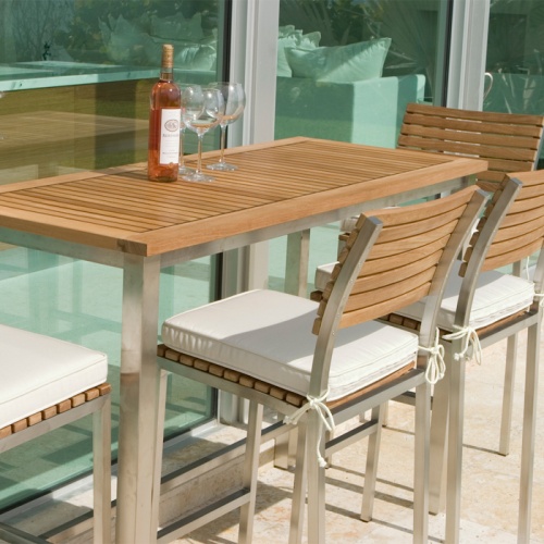 70167 Vogue 7 piece Bar Table Set right view on concrete patio showing optional canvas color seat cushion with wine bottle and 3 wine glasses on table in front of window facing indoors