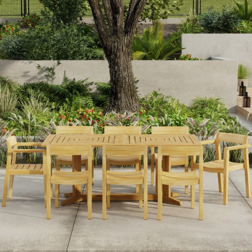 70462 Pyramid Horizon 9 pc Teak Dining Set of Pyramid Rectangle Dining Table and 2 Horizon Dining Armchairs and 6 Side Chairs in angled side view on patio with landscape plants in background