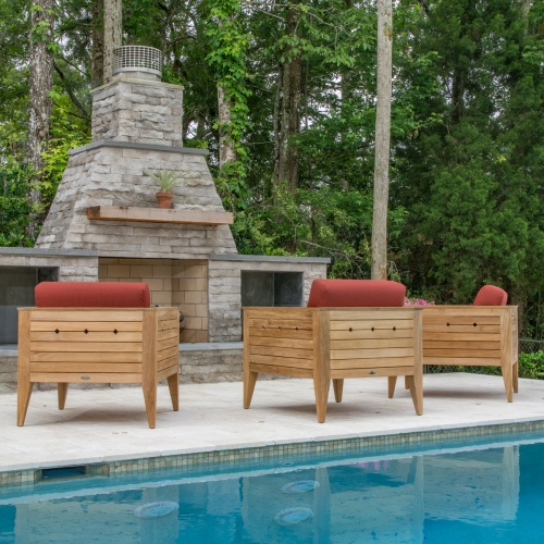 70506 Craftsman three piece teak lounge set on patio facing outdoor fireplace with potted plant on mantle and pool in front of set with lush vegetation and trees in  background