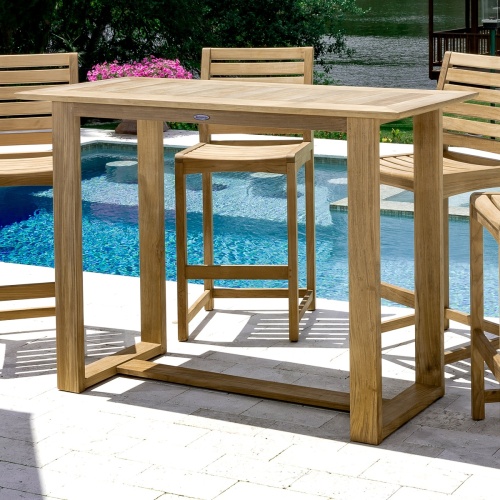 70512 Somerset 5 piece teak Barstool and Bar Set closeup view of 4 barstools in front of pool facing table with flowering plants screened porch by lake and trees in background