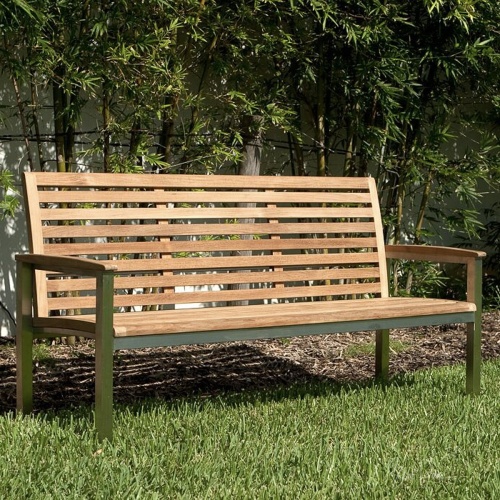 70779 Vogue teak and stainless steel 5 foot long bench side angled on grass lawn with bamboo trees and building in back