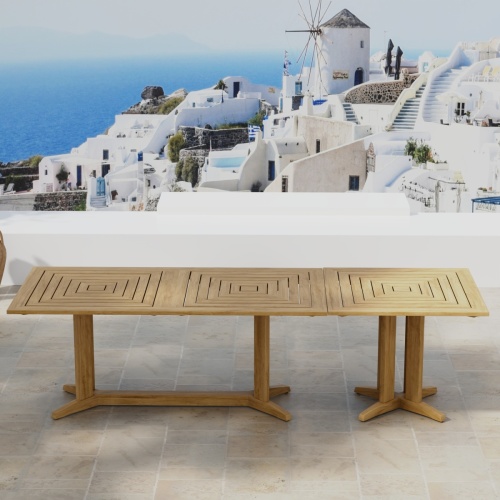 70936 Pyramid Teak Table Set of Pyramid Teak Rectangular Table and Square Table in angled side view on outdoor terrace with houses and ocean in background
