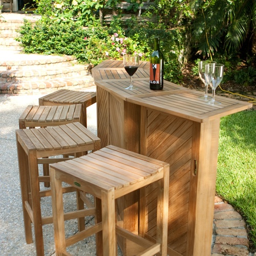 12110RF Somerset Backless Barstool Refurbished with teak Somerset Bar with 3 wine glasses and wine and 4 Somerset Backless Barstools in side angled view on patio with grass in back