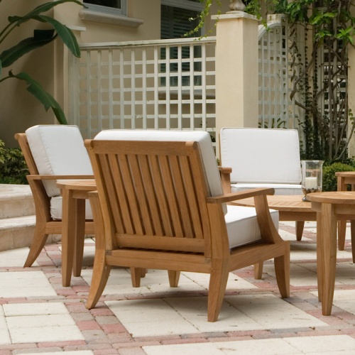 12152DP Laguna teak lounge chair three with two side tables and coffee table on paver patio with lattice fence building and trees in background