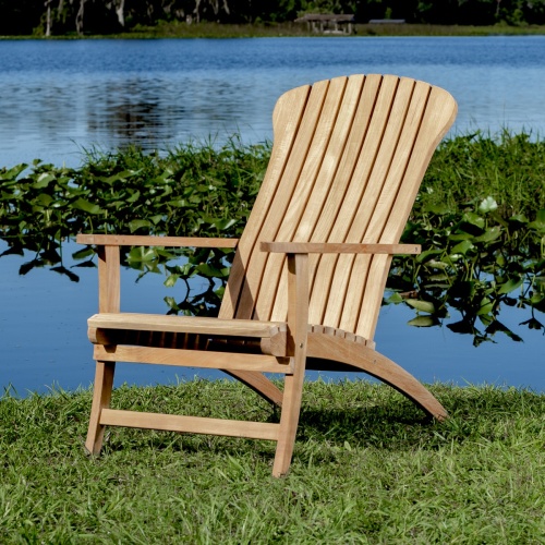 12221 Adirondack teak chair angled on green grass side view with lake with water lilies and plants in background