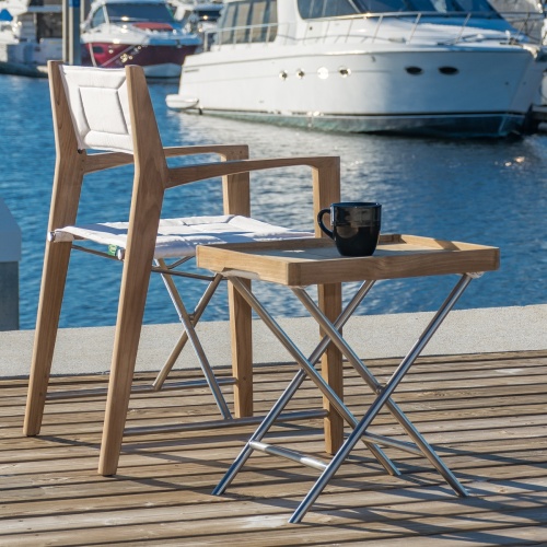 12915RF Refurbished Odyssey Director Chair rear right side view facing water on a wood dock next to side table with coffee cup on top with yachts and boats in background