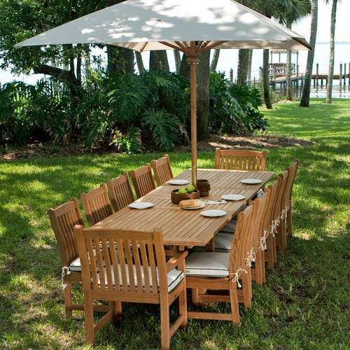 70017 Grand Veranda 13 piece Teak Dining Set with canvas rectangular umbrella on grass over looking lake