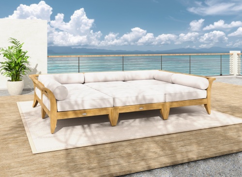 70100 Aman Dais 6 pc Daybed Set  with cushions front view on wood deck and stone patio next to potted tree and blue sky and ocean background