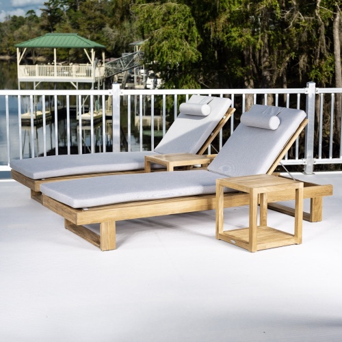 70308 Horizon teak double chaise set with cushions left side angled on concrete deck with metal railing trees boathouse and dock in background