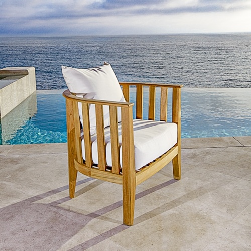 70421 kafelonia teak lounge chair with cushions side angled on stone patio with pool ocean and blue sky background