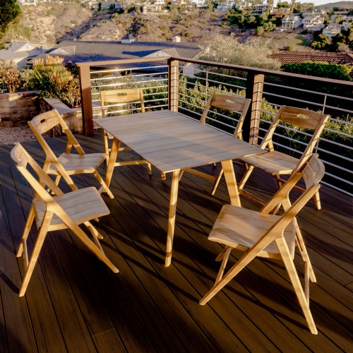 70518 Surf teak 7 piece folding Dining Set angled view on wood deck overlooking homes in background