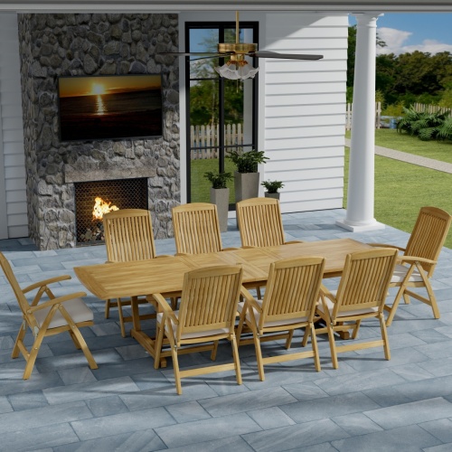 70796 Teak 9 piece Reclining Dining Set in angled aerial view on slate tiled patio in front of a fireplace and window of house and grass and trees in the background  