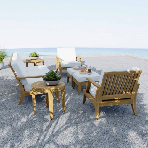 70871 Laguna 7 pc Conversation Set side view on a stone rock terrace with 3 potted plants and magazine and plates on ottoman with ocean in background 