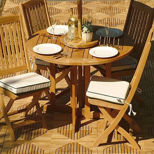 15623 Barbuda Folding Round Table with 4 place settings on top and 4 folding teak chairs on teak tiles in background
