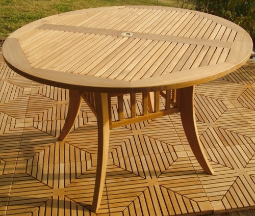 70030 Grand Hyatt round dining table angled side view on teak tile floor with grass background