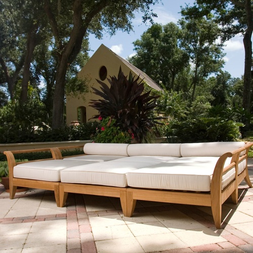 70100 Aman Dais 6 pc Daybed Set front angled showing two corner three end pieces and one ottoman on stone patio with trees plants and house in background